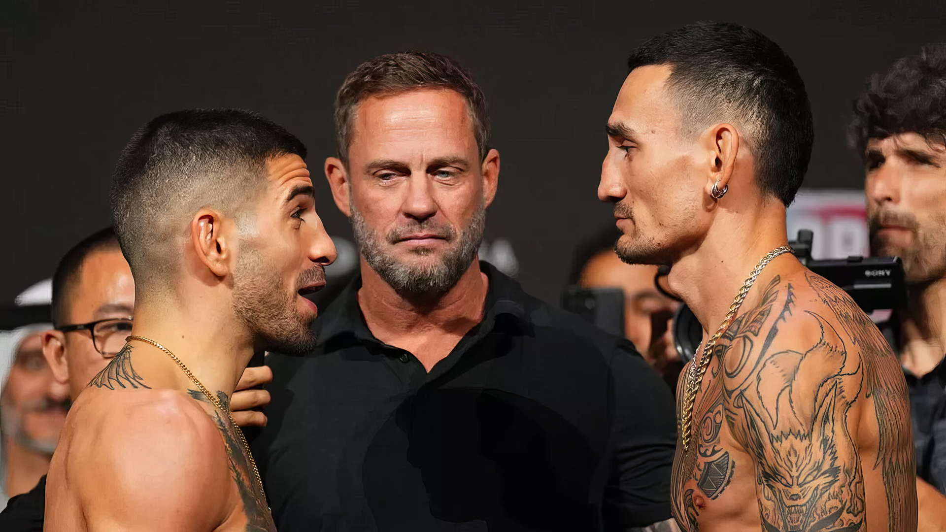 Ilia Topuria and Max Holloway face off at an MMA weigh-in, with a referee in between them, showcasing the intensity and anticipation of their upcoming UFC match.