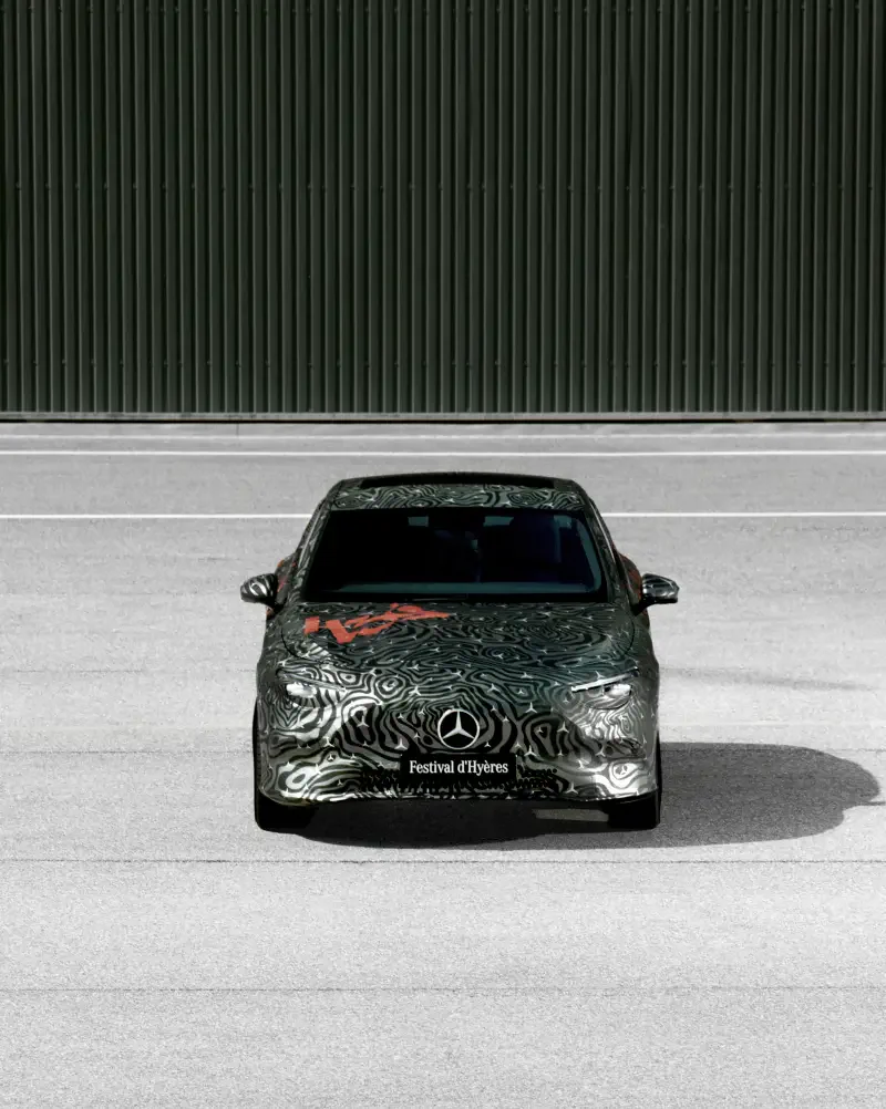 A Mercedes-Benz CLA emphasizes its sleek design with a distinctive patterned wrap, showcased against a simple pavement backdrop.