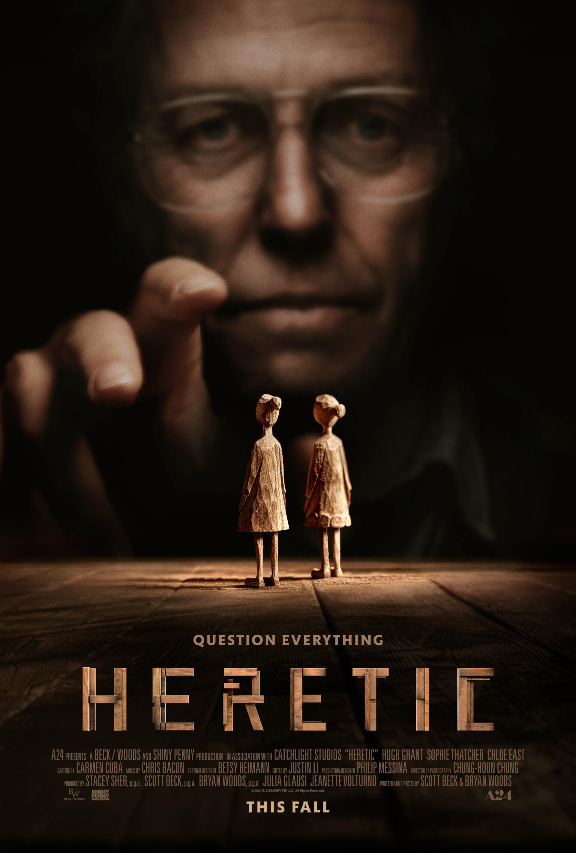 A dark movie poster for Heretic (2024) featuring Hugh Grant, depicting two puppet-like figures in the foreground and a looming, mysterious figure in the background. Question Everything tagline included.