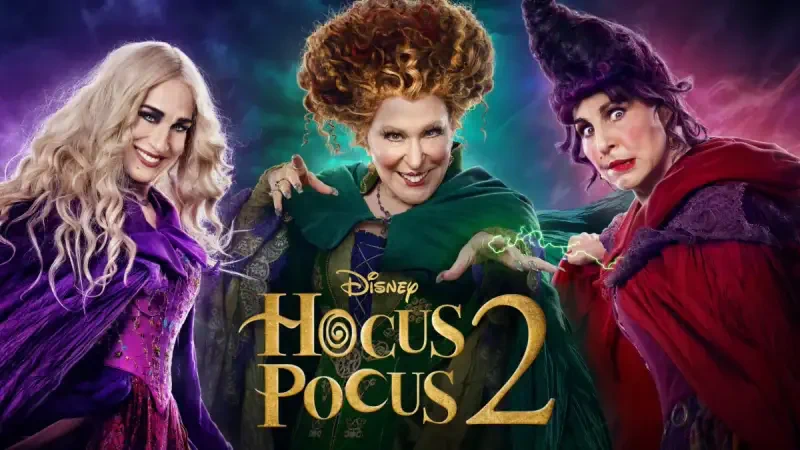 Three witches stand side by side in vibrant, themed costumes, showcasing their distinctive hairstyles and expressions, with the title Hocus Pocus 2 prominently displayed above.