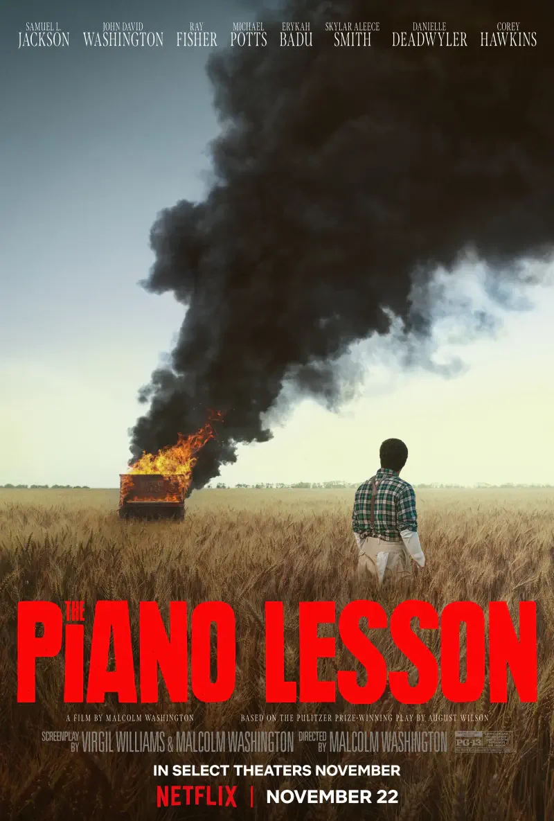 A figure stands in a field, gazing at a burning piano, with smoke rising against the sky. The poster promotes the movie The Piano Lesson, coming to theaters and Netflix on November 22.
