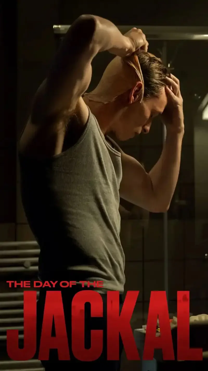 A man in a sleeveless shirt styles his hair in a dimly lit bathroom, showcasing a moment from the TV show *The Day of the Jackal* (2024).