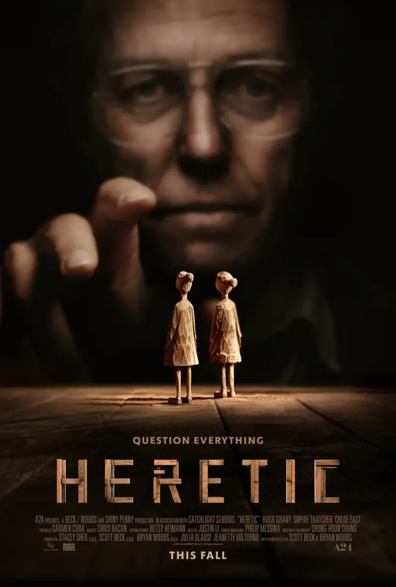 A dark movie poster for Heretic (2024) featuring Hugh Grant, depicting two puppet-like figures in the foreground and a looming, mysterious figure in the background. Question Everything tagline included.