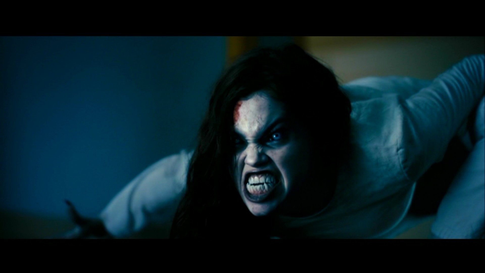 Close-up of a snarling pale vampire woman crawling toward the camera, bared fangs and wild hair — still from the movie Underworld: Evolution.