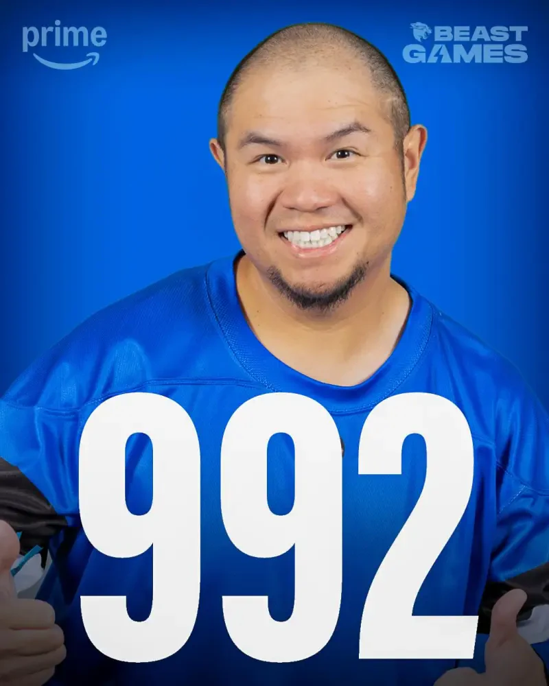 A smiling contestant in a blue shirt gives thumbs up, featuring the number 992. The image is promotional for the TV show Beast Games.