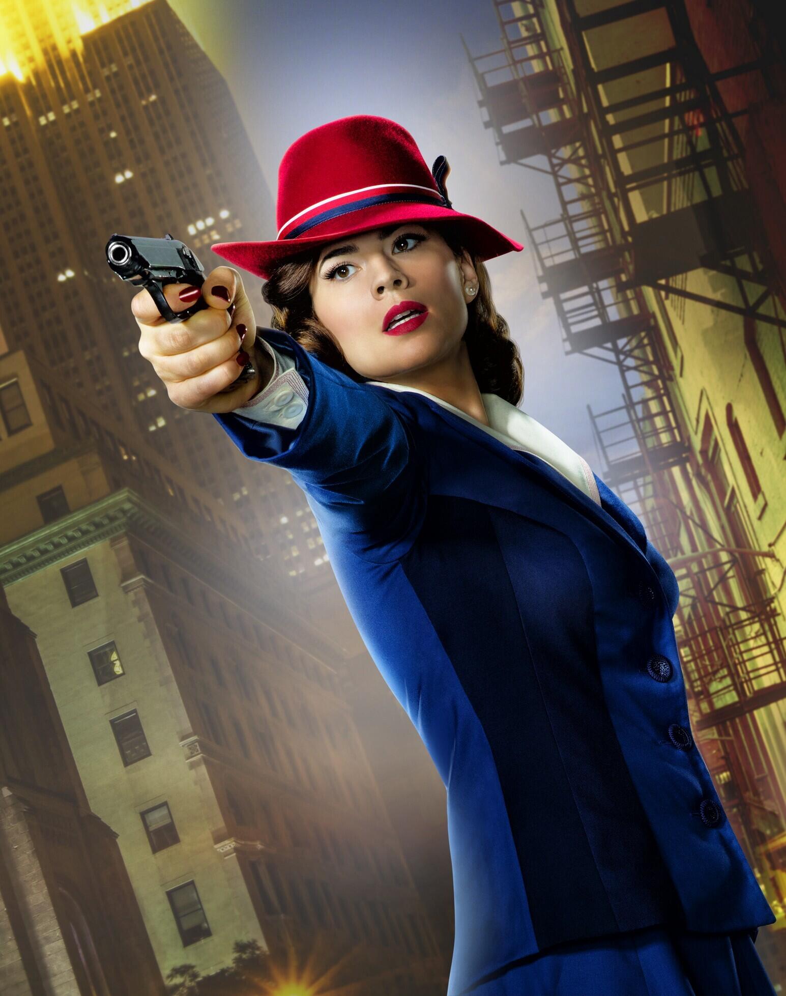 Promotional image for the TV show Agent Carter: a 1940s-style woman in a blue suit and red hat points a pistol toward the viewer against a nighttime urban backdrop.