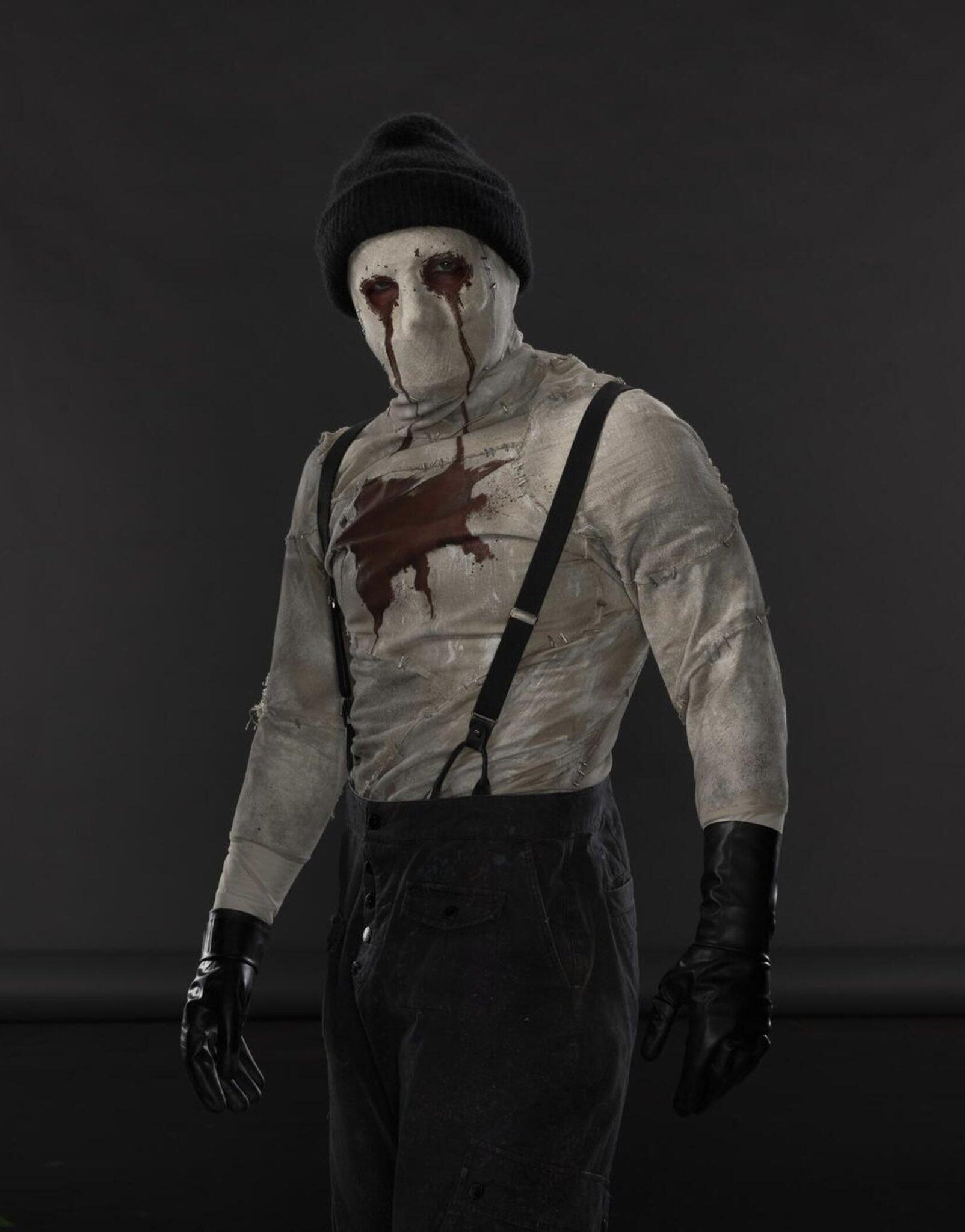 Bandaged masked figure with blood-streaked eyes and a chest stain, wearing suspenders, beanie and gloves — from Daredevil: Born Again (TV show).
