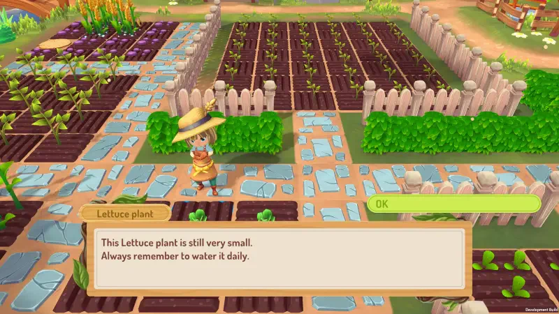 A character stands in a colorful farm setting in Sugardew Island, tending to small lettuce plants while reminders to water them appear on-screen.