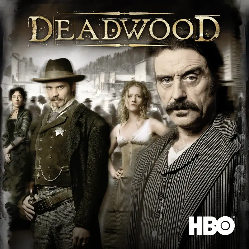 Poster for Deadwood, TV show: four frontier figures in 19th-century attire stand before a dusty town backdrop, with the Deadwood title and HBO logo prominent.