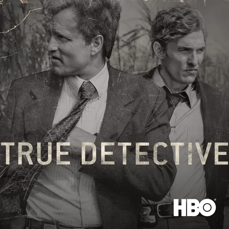 HBO's True Detective TV show promo: two serious detectives in suits stand among tall brush in a gritty, monochrome image with the series title across the frame.