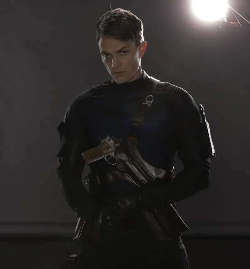 Brooding costumed figure in black tactical gear holding holstered pistols beneath a spotlight — promotional image for the TV show Daredevil: Born Again.