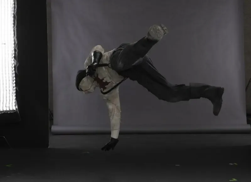 Performer in Daredevil: Born Again (TV show) costume captured mid-air doing a one-handed flip against a gray studio backdrop.