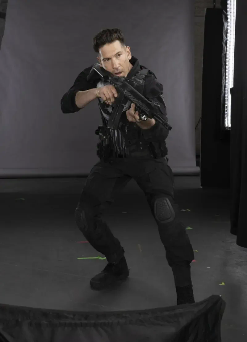 Person in black tactical gear aiming a rifle on a studio set, behind-the-scenes image for the TV show Daredevil: Born Again.