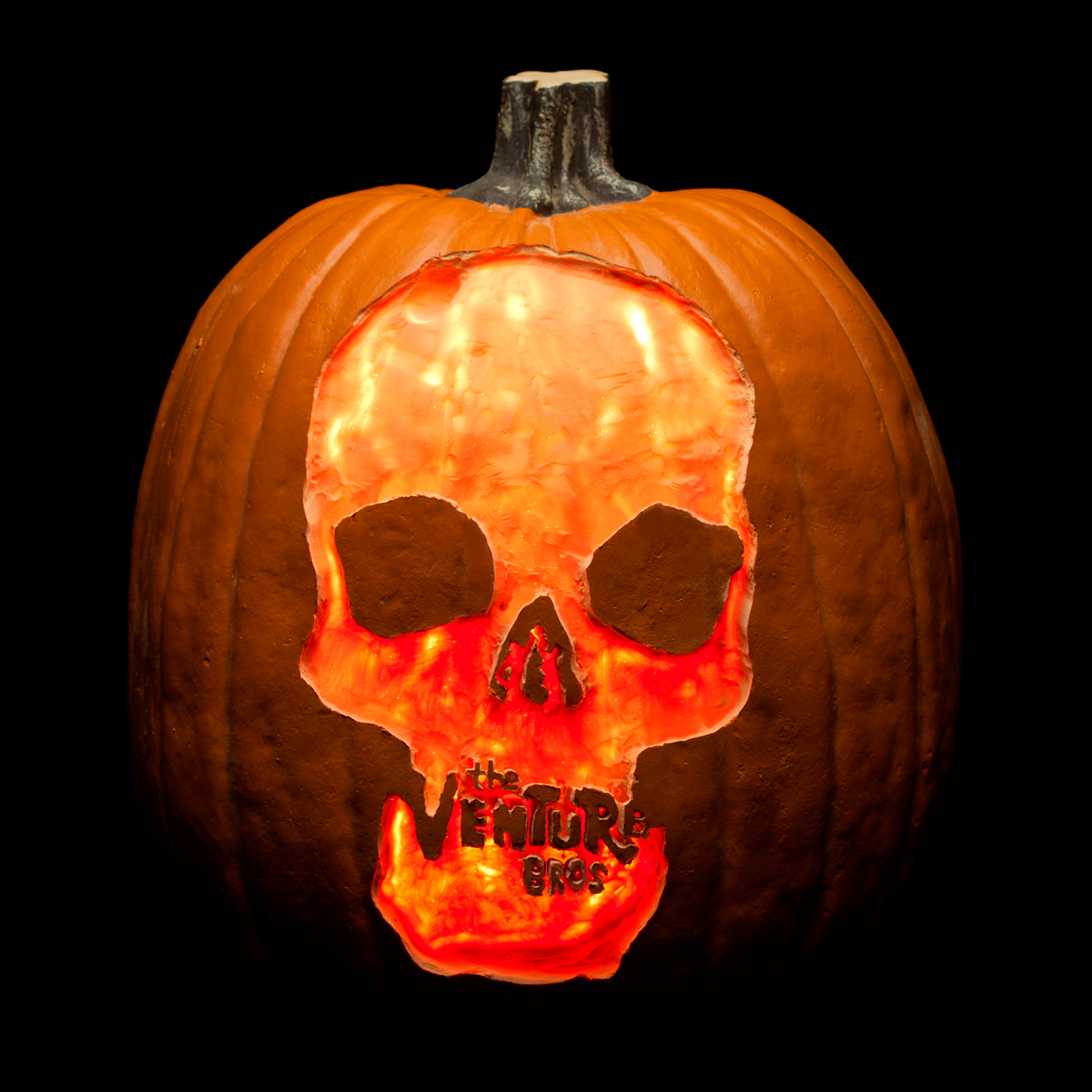 Glowing jack-o'-lantern carved with a skull and the The Venture Bros. TV show logo.
