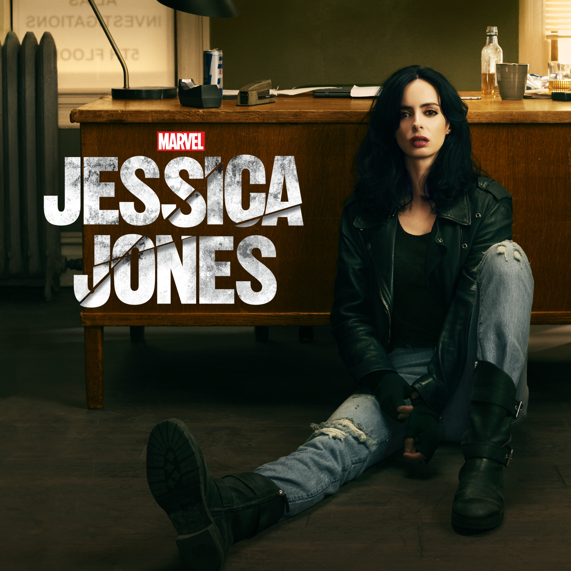 Jessica Jones (TV show) poster: Jessica sits on an office floor in a leather jacket and ripped jeans, leaning against a desk with the show's logo beside her.