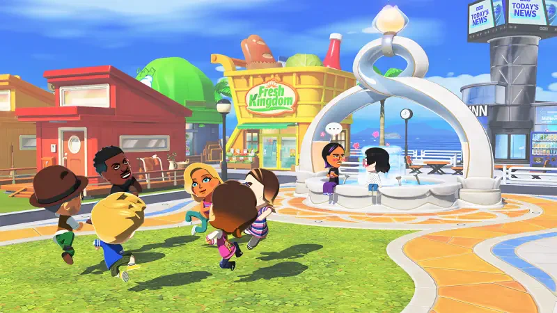Tomodachi Life simulation game scene: colorful town square with stylized characters laughing and dancing around a decorative fountain, shops and benches under a sunny blue sky.