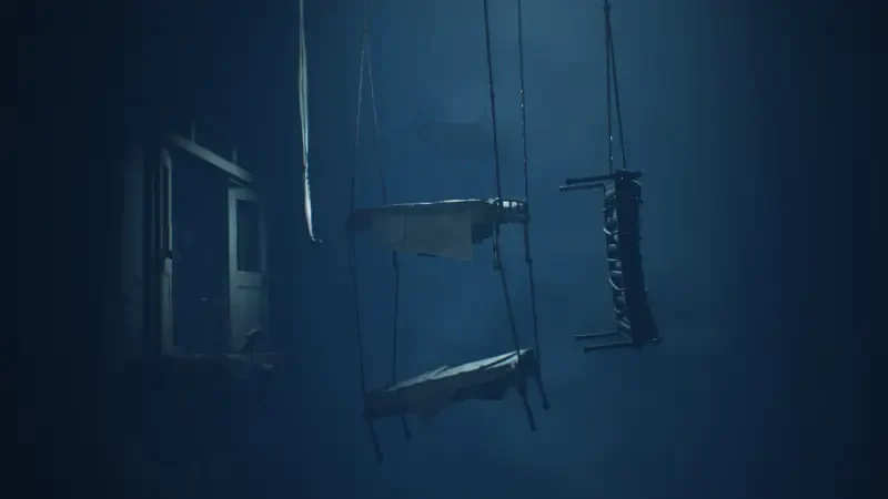 Little Nightmares II: dim blue room with three hanging beds/straps suspended from the ceiling and a shadowy doorway to the left, creating an eerie, submerged atmosphere.