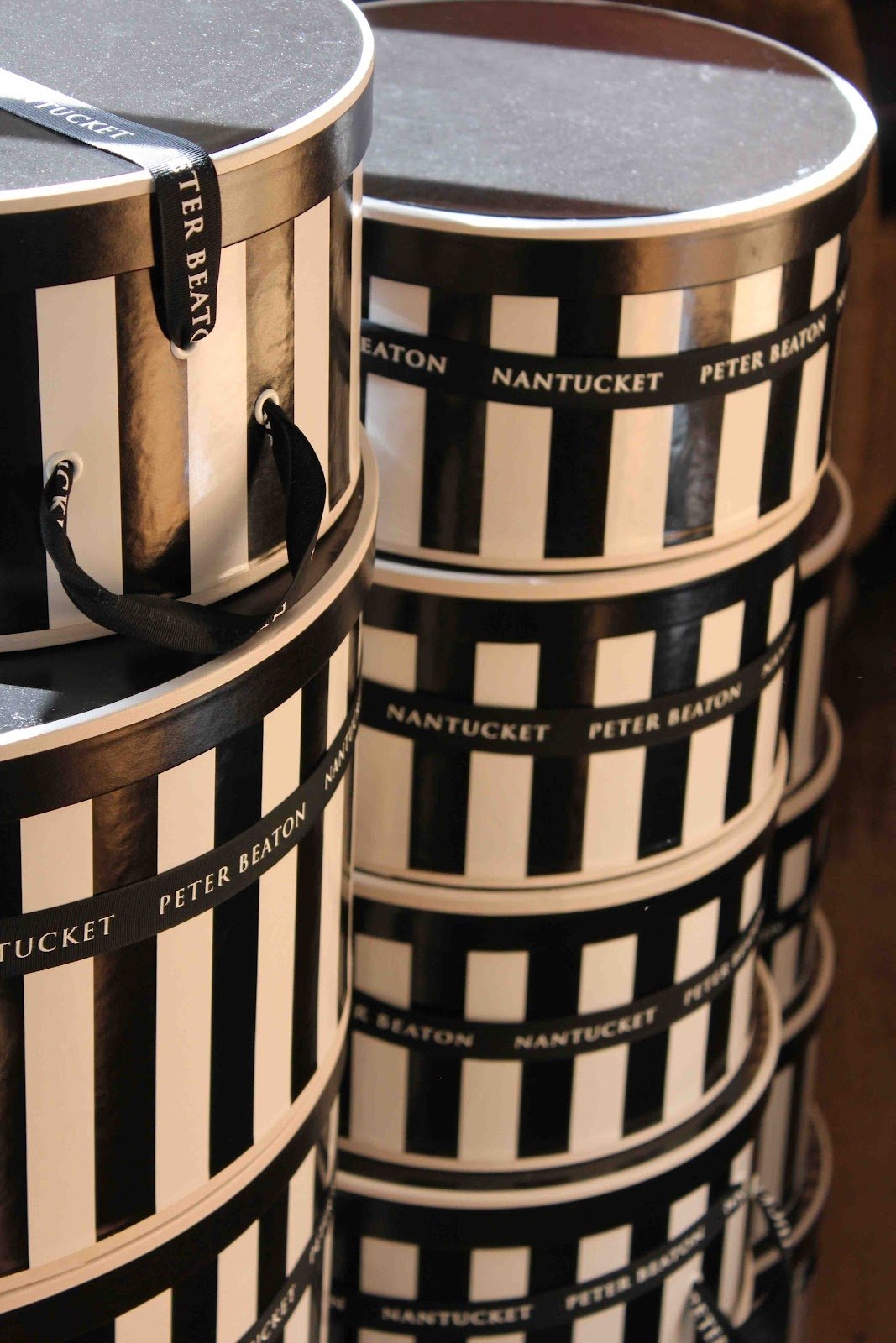 Abstract man-made arrangement of stacked black-and-white striped hat boxes with rope handles and Nantucket Peter Beaton bands, forming a repeating geometric cylindrical pattern.