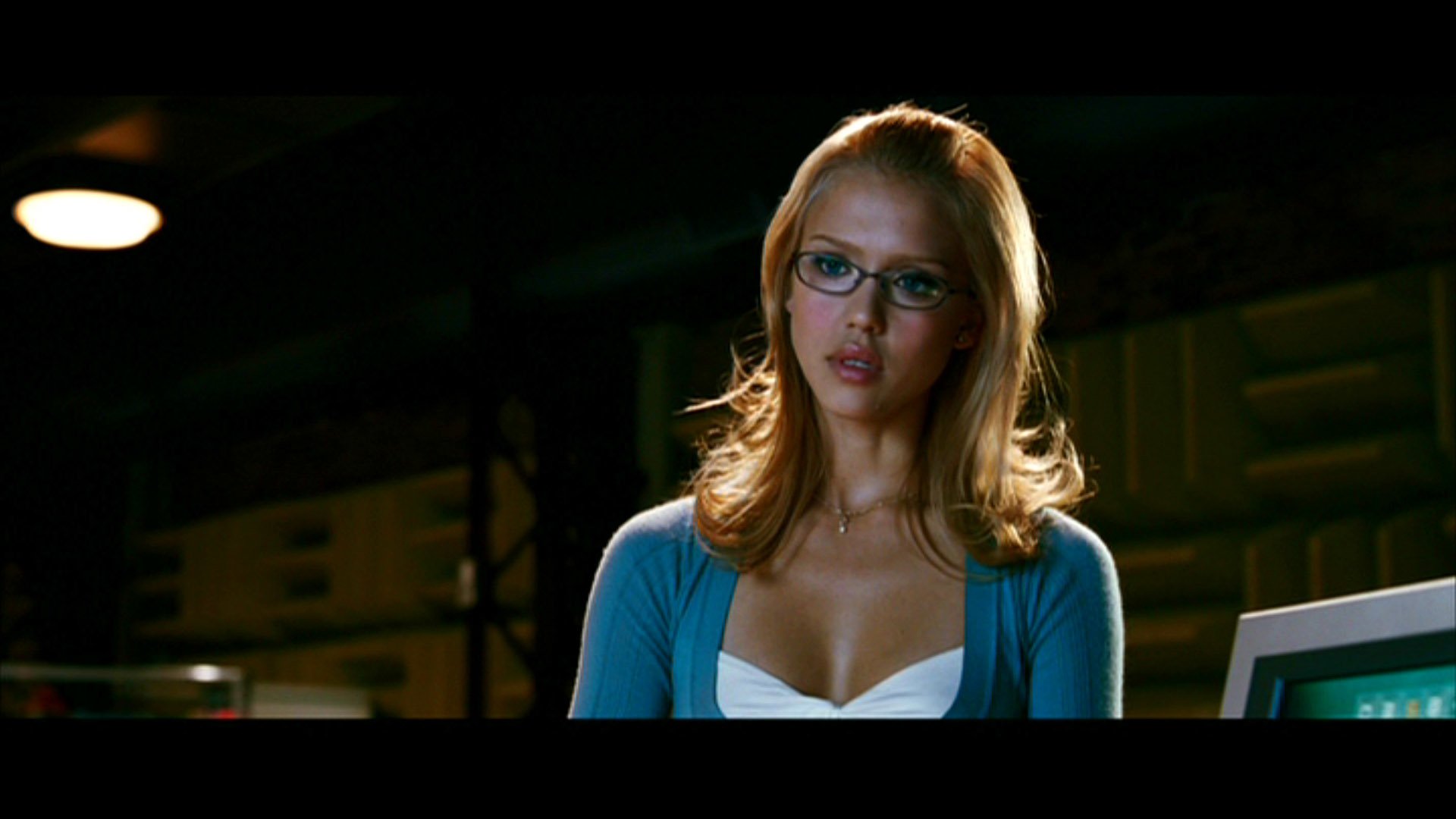 Young blonde woman with glasses and a cardigan in a dim control room — scene from the movie Fantastic Four.